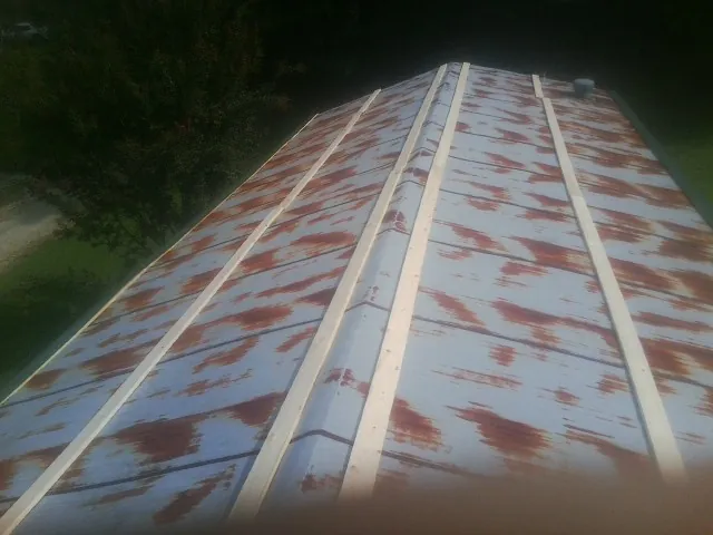 Rusted metal roof panels with new wood purlins before replacement — Storm Damage Roof Repair in Marne by Roofing Brothers