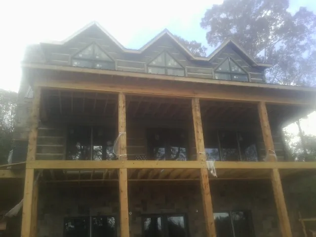 Dormers and porch framing on a large log home under construction — Roof Coating work by our crew in Marne