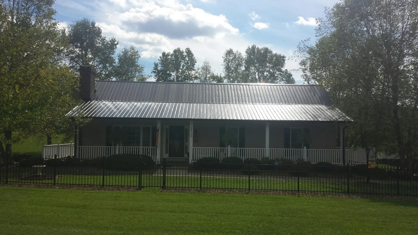 Gray metal roof on a brick ranch with a full width front porch — Gutter Guard Installation work by our crew in Marne