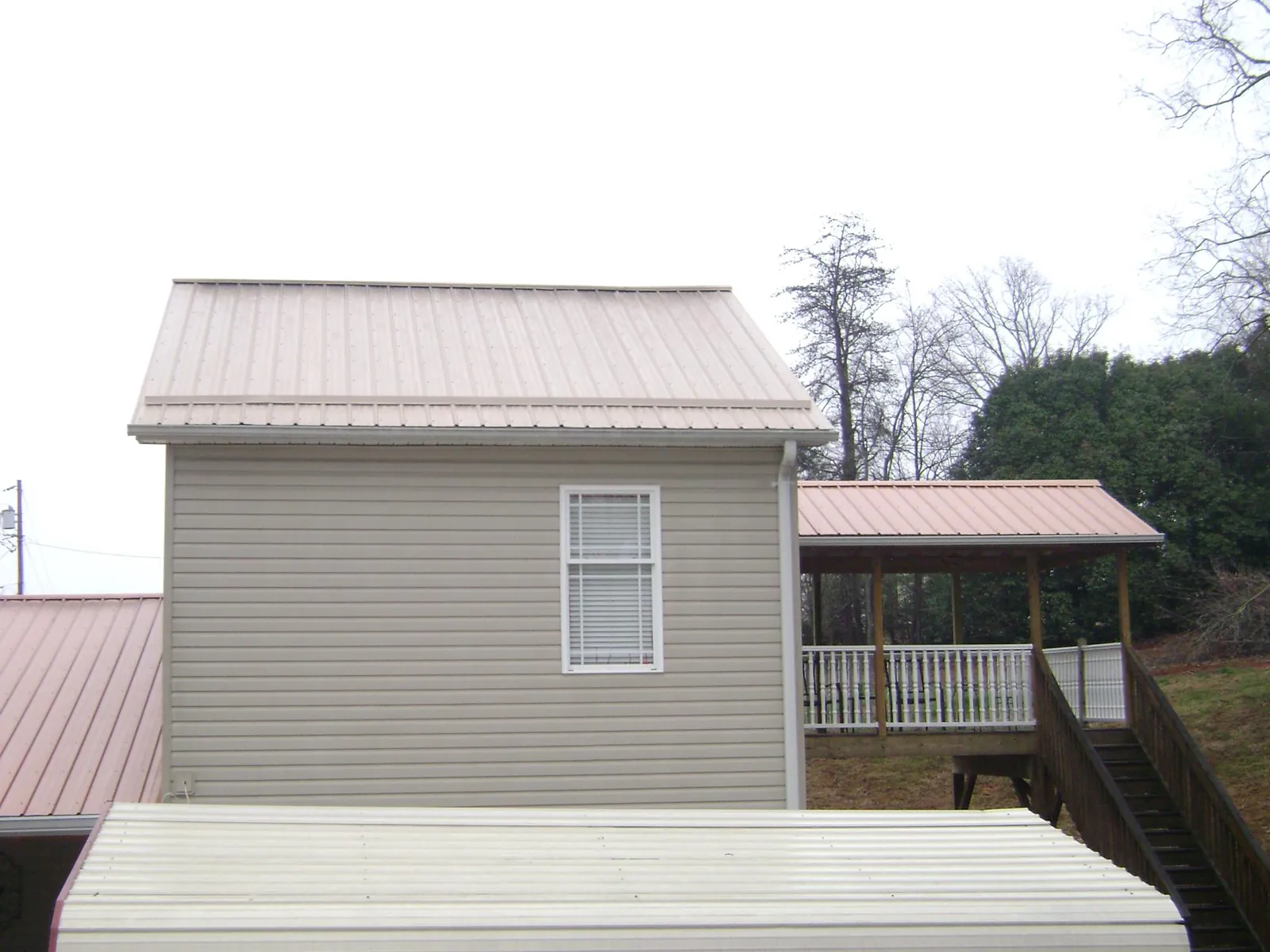 Tan metal roofs on a two story addition and attached porch, from a Roof Replacement job in Marne