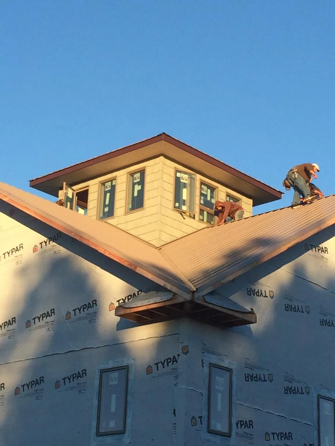 Roofers working around a rooftop cupola on a new metal roof at sunset — Roof Waterproofing in Marne by Roofing Brothers